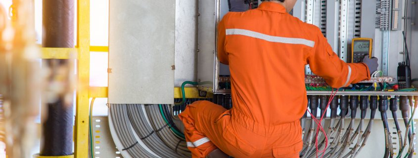 Electrical and instrument technician troubleshooting on programmable logic controller of oil and gas production system, offshore oil rig worker.